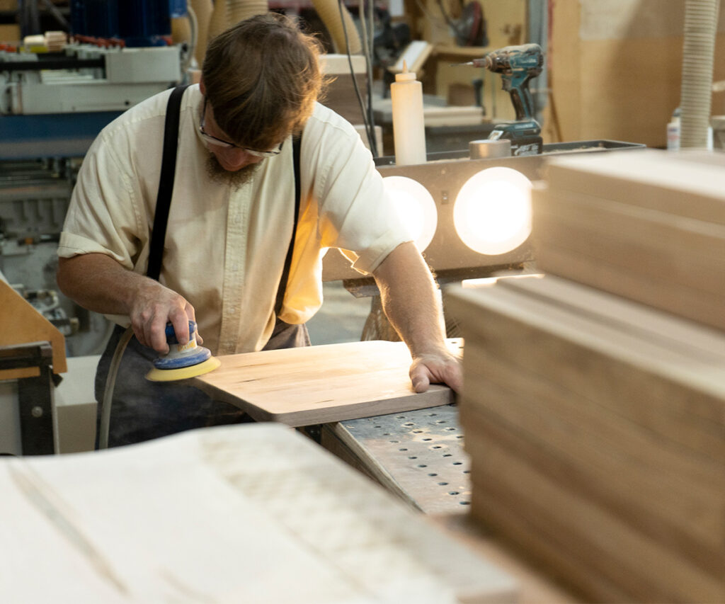Amish craftsman sanding wood components