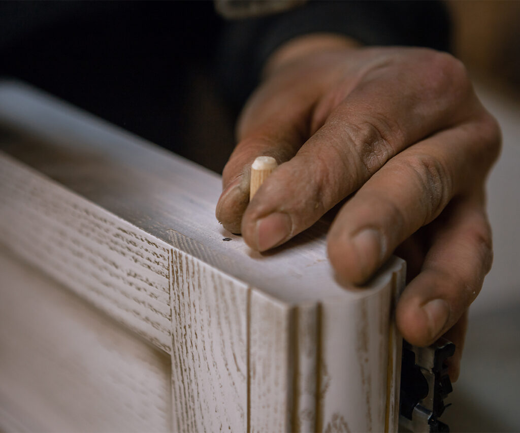 hand with dowel pin: Amish furniture joinery: dowel pin securing solid wood frame.