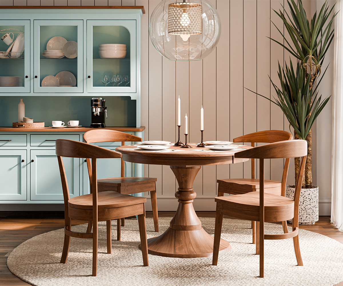 Round hardwood dining table with four chairs in bright kitchen nook.