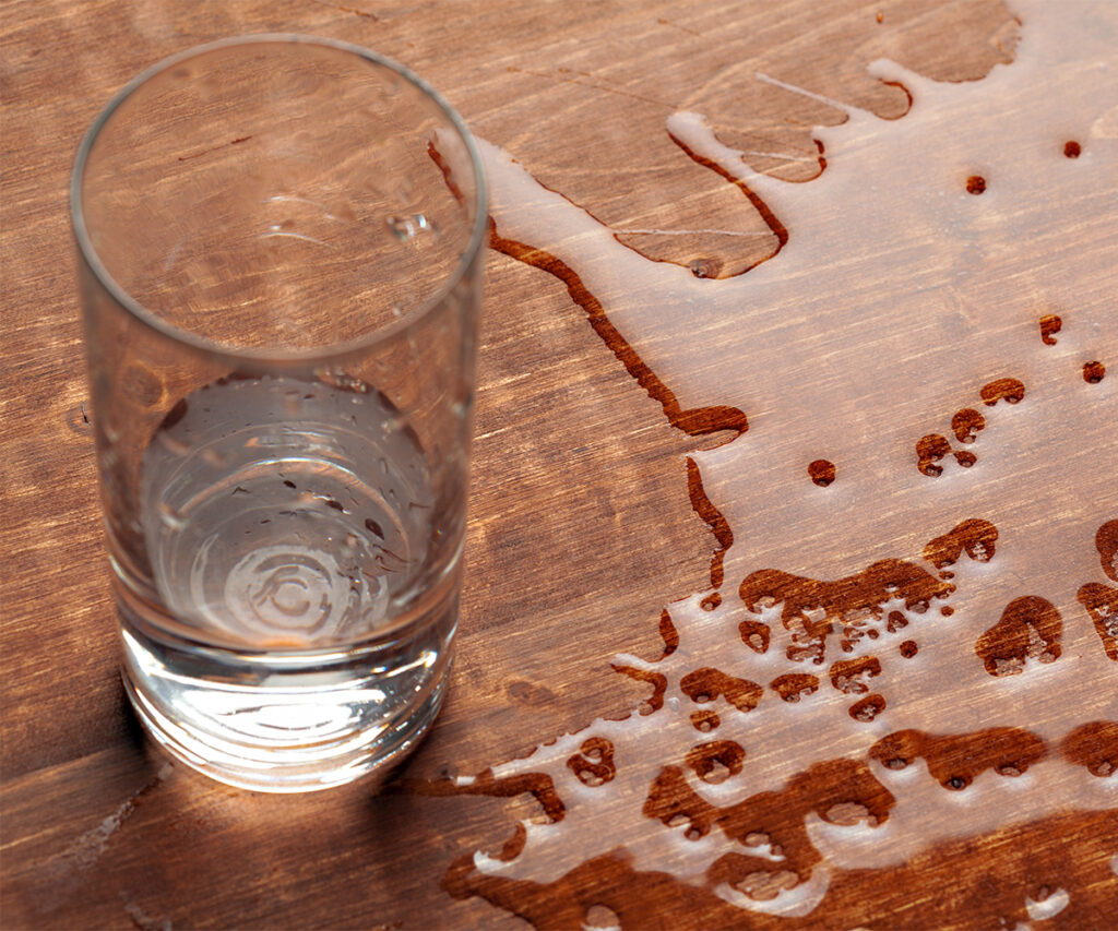 Amish furniture tabletop with spilled water, showing why quick cleanup prevents damage.