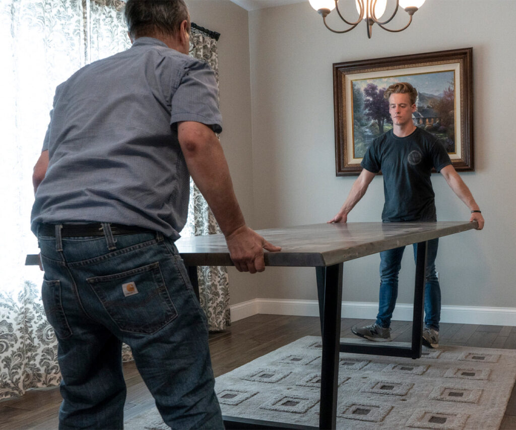 White-glove furniture delivery team carefully positioning solid wood table