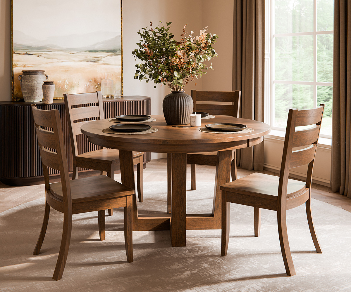 Round wood dining table and four chairs in a warm, intentional dining room.
